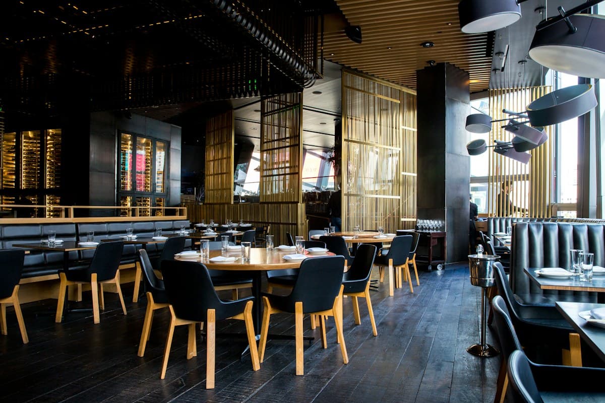Warm restaurant interior with wood tables and greenery